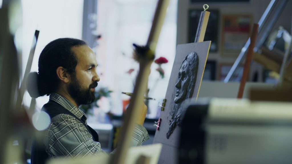 Artist realizând un portret după fotografie veche în atelier de pictură